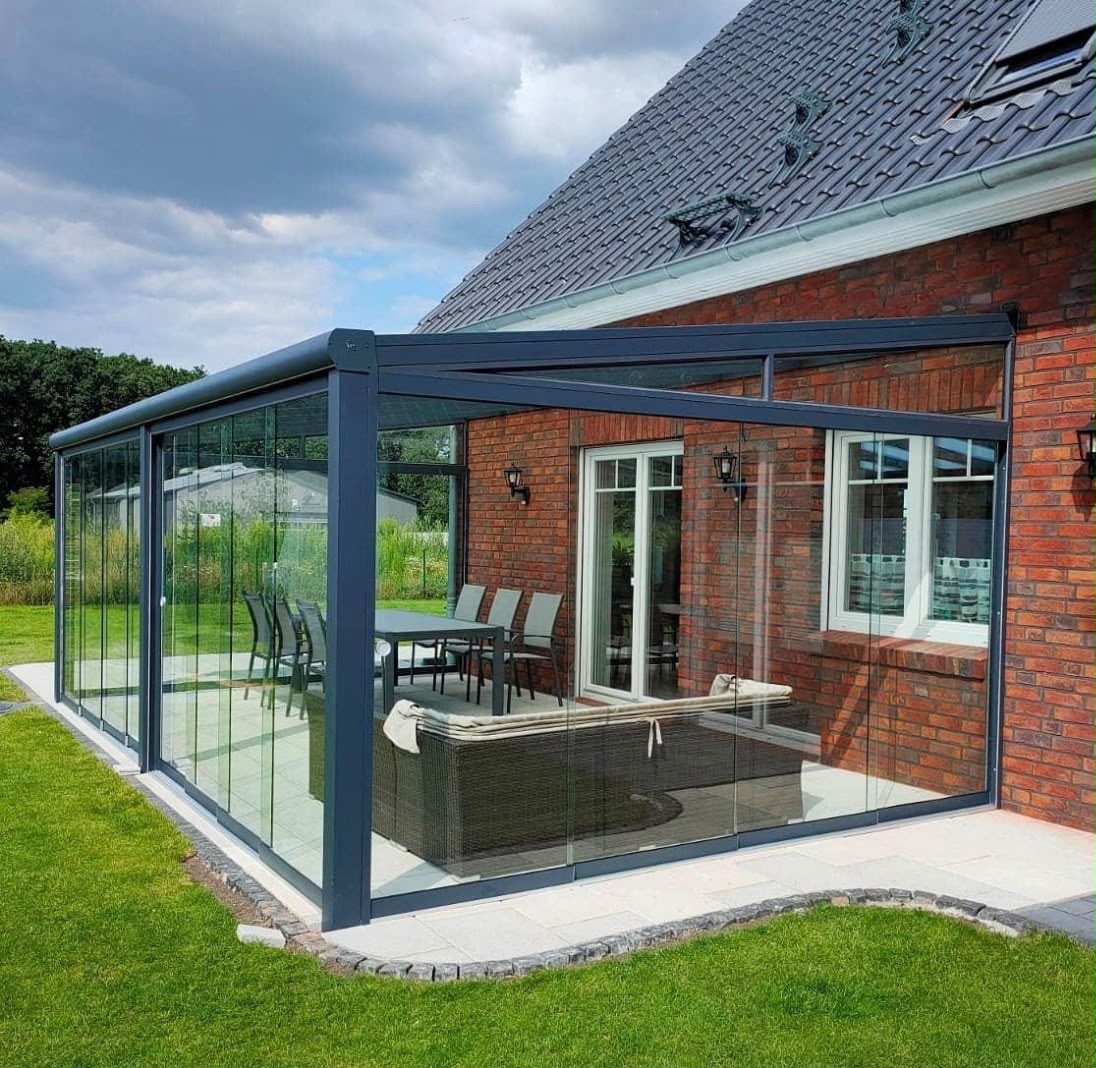 Sommergarten mit rundum Glasschiebewänden an einem Backsteinhaus
